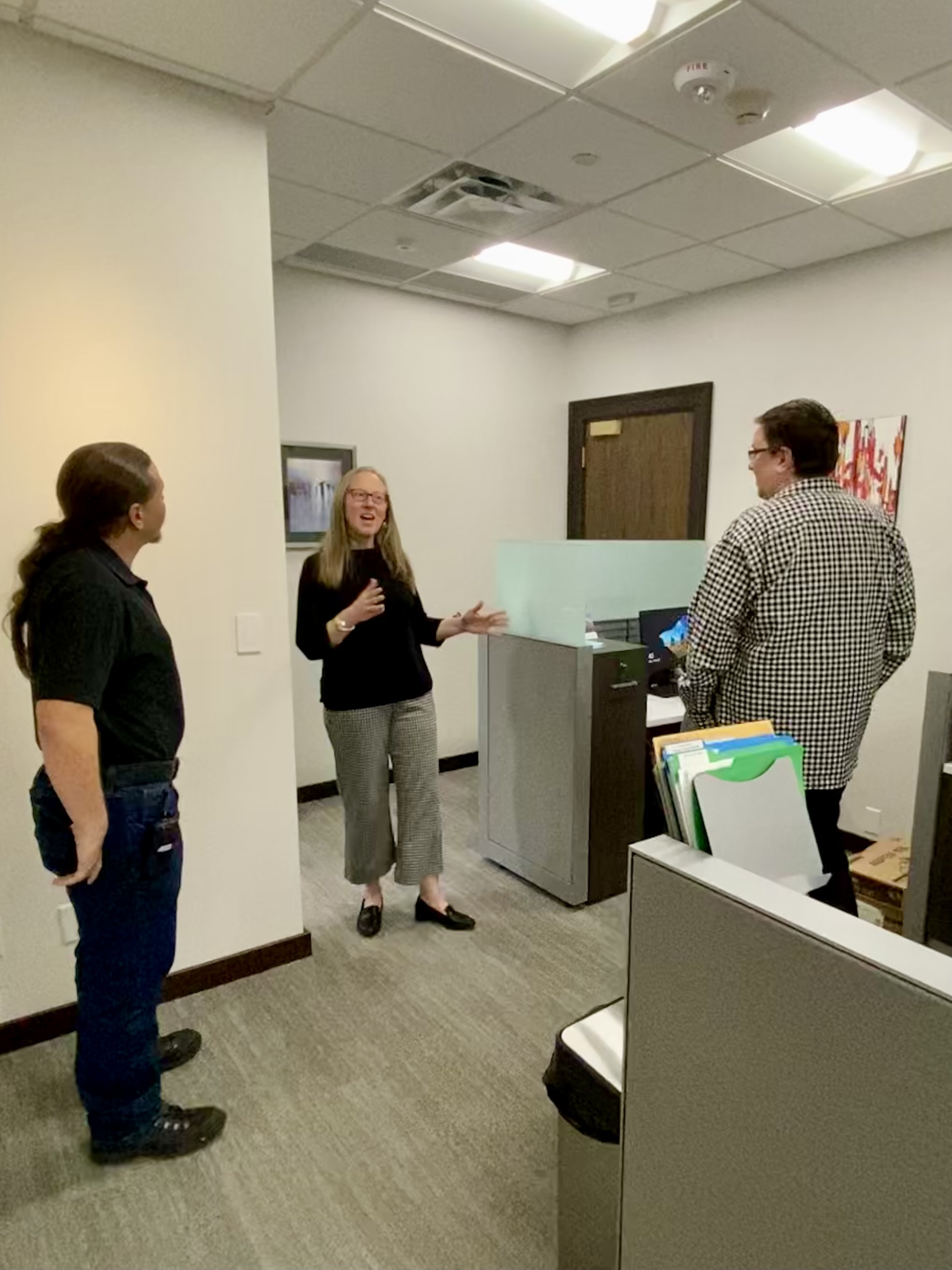 Lori McDonald, Justin Serrano, and Jeremy Wilkerson talk in front of the painting.