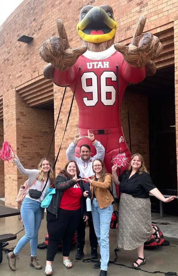 five staff members pose for photo in front of a large inflatable Swoop (the University of Utah Mascot).