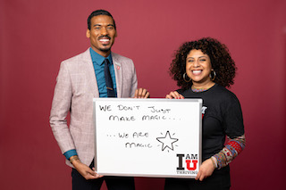 A picture of a Black man and woman, together holding a hand-written white board that says 