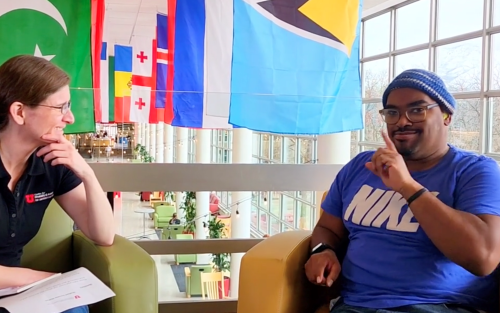 picture of LJ Williams sitting in a chair across from his advisor, Charity, using sign language.