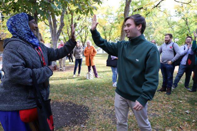 Two people high-five after playing rock-paper-scissors outside the Union.