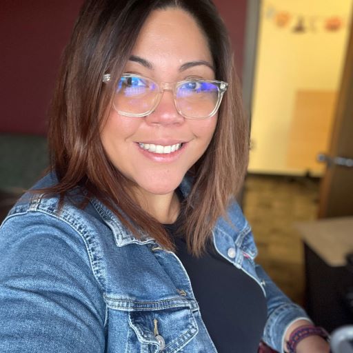 Selfie of Claudia Navarro with a jean jacket, black shirt, and glasses on. 