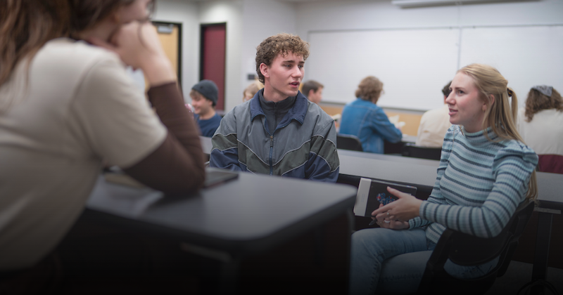 Students sitting around a table, each with their own uinque presentation and brand