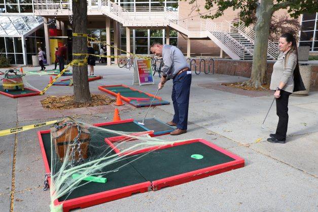 Two people playing mini golf outside the Union.